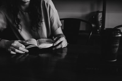 灰度女人读一本书在木桌上的照片
